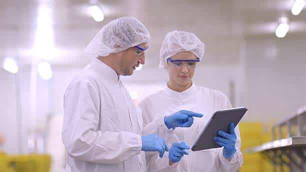 Deux auditeurs qualité en tenue d’hygiène analysant des constats d’audit sur tablette en usine agroalimentaire