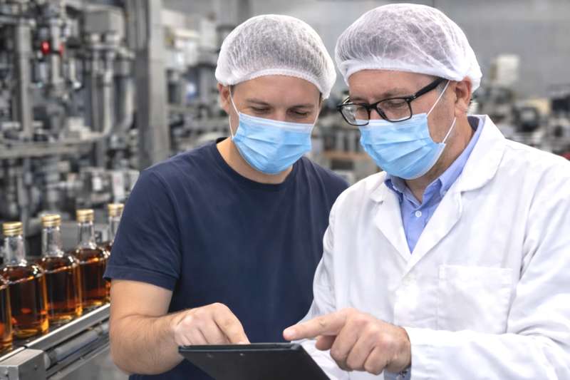 Audit qualité agroalimentaire sur ligne d’embouteillage : opérateur et auditeur contrôlant les données de production en environnement IFS et HACCP